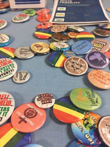 One of many informative tables set up in the A building hallway during the Symposium held a variety of social justice themed pins. 