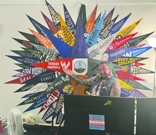 Counseling Assistant Ducky Jones showing the wall of colleges in the counseling office. 
