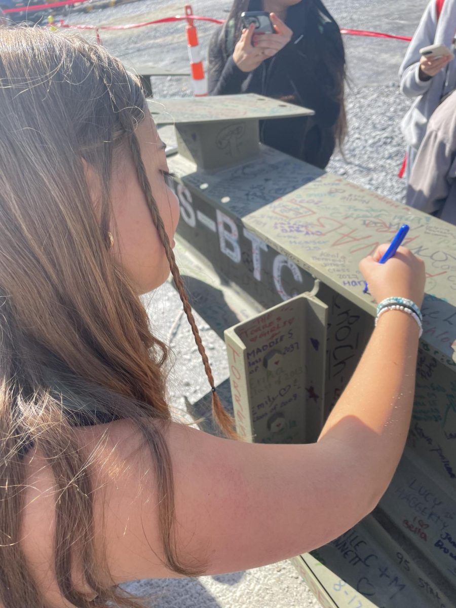 Student Government member Harper Roof '27 signs the final beam before it is hoisted into place on the new BHS/BTC building. 