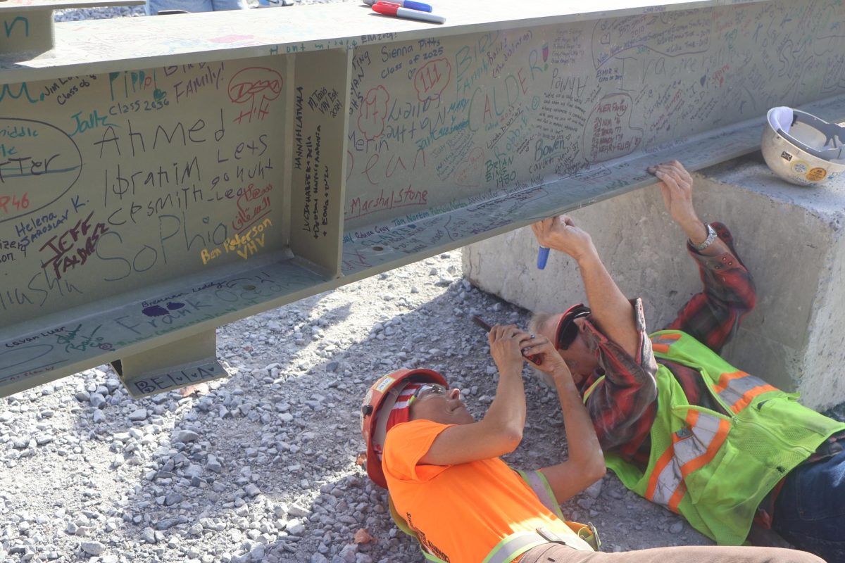 Workers get creative to find a spot on the final beam that hasn't been signed yet. 