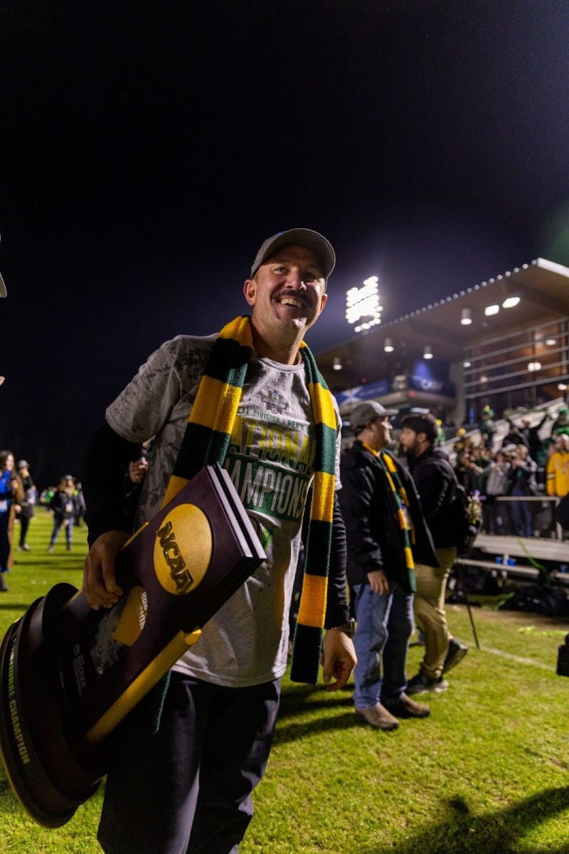 UVM Men's Soccer Head Coach Rob Dow holding the NCAA National Championship trophy after the Catamount's historic win. 