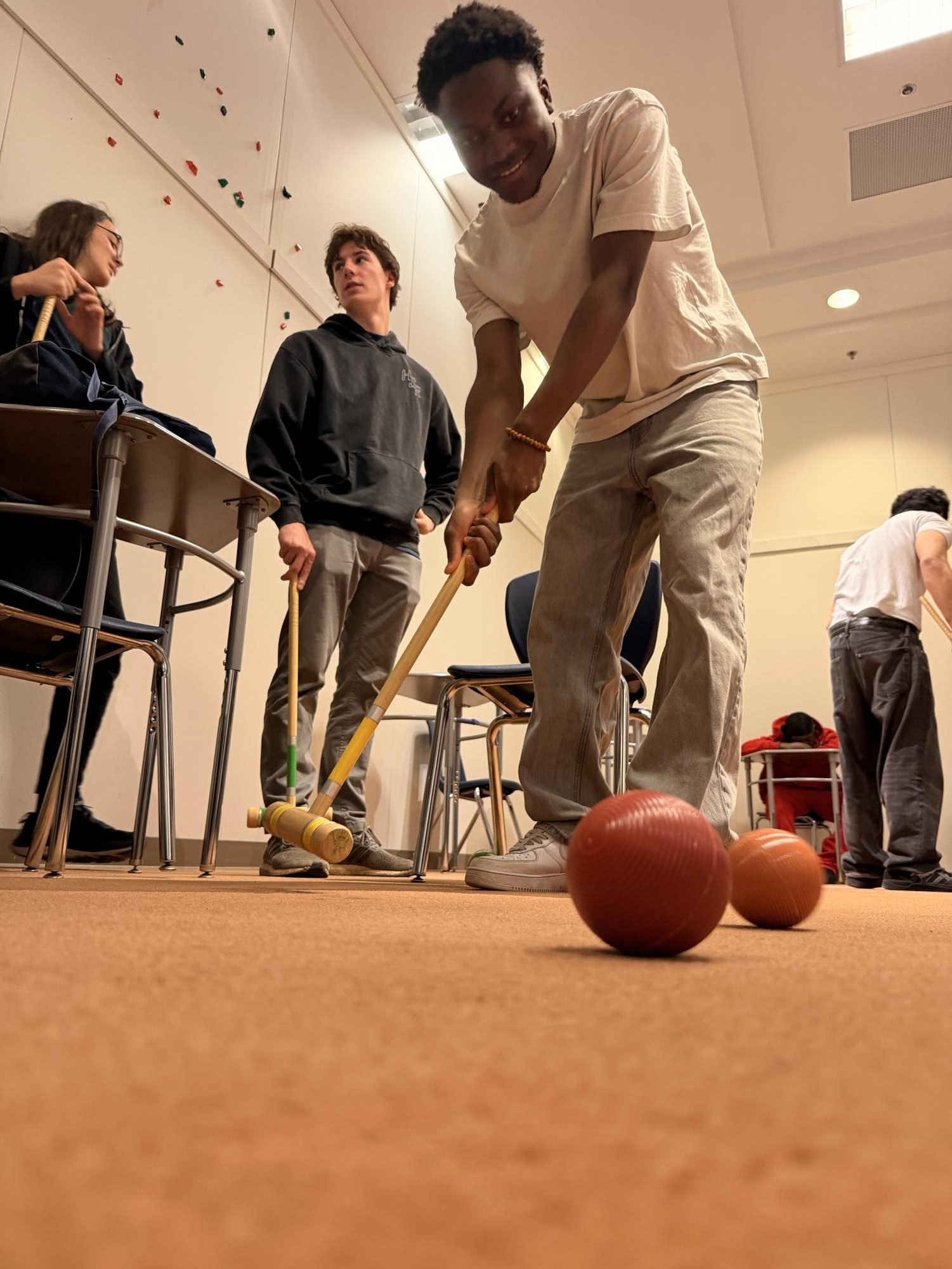 Dunia Shabani '26 playing croquet in the classroom used for PE at BHS. 